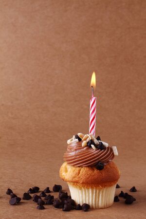 birthday cupcake with candle on chocolate backgroundの写真素材