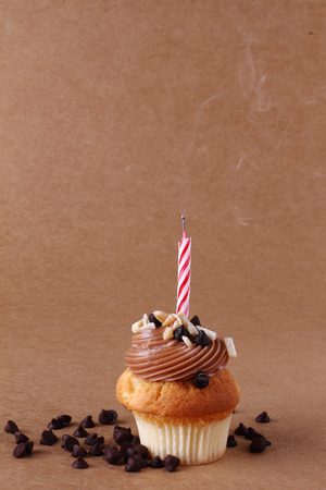 birthday cupcake with candle on chocolate backgroundの写真素材
