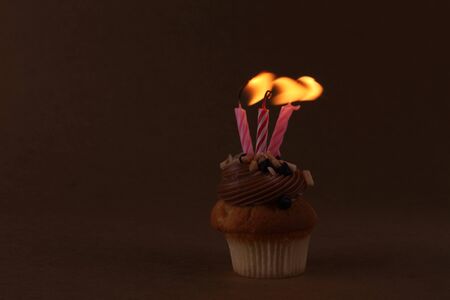 birthday cupcake with candles on dark backgroundの写真素材