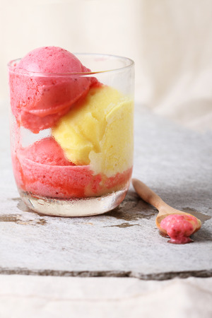 strawberry and passion fruit sherbet in a glass with spoonの写真素材