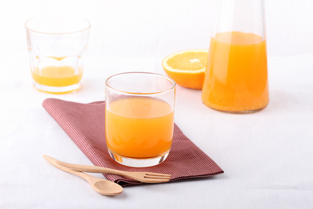 glass of orange on napkin and bottle of orange on white backgroundの写真素材