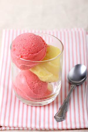 strawberry and passion fruit sherbet in a glass with spoonの写真素材