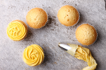 homemade cupcake with buttercup color frosting and piping bagの写真素材