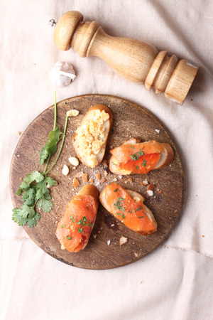 Delicious homemade scrambled eggs with smoked salmon garnished with a fresh parsley leaf on rustic woodの写真素材