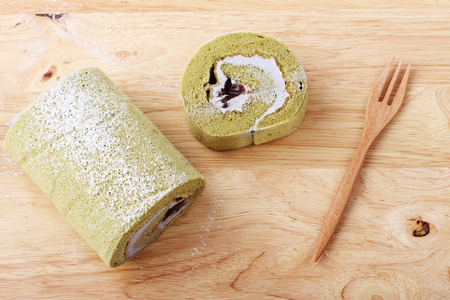 Green Tea Swiss Roll Cake on wooden cutting board with forkの写真素材