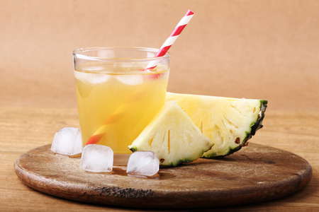 sliced pineapple with a glass of pineapple juice on wooden background