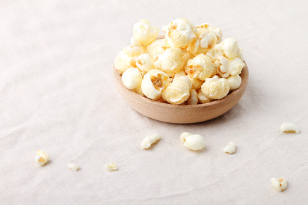 caramel popcorn in wooden bowl on table with napkinの写真素材