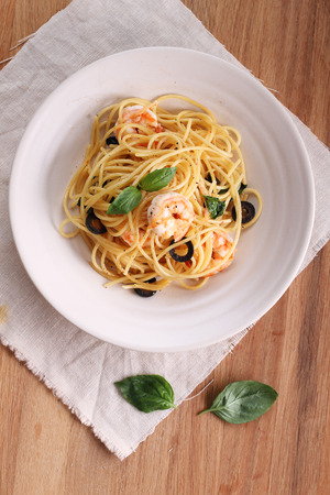 spaghetti pasta with shrimps and sweet basil on wooden tableの写真素材