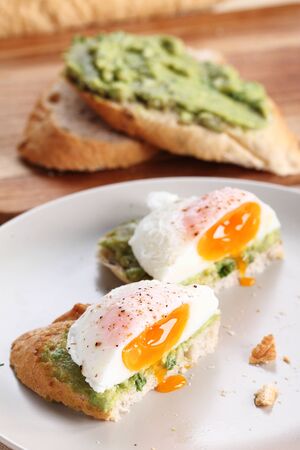 Breakfast, poached eggs with avocado salad on toastの写真素材