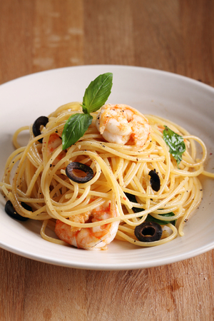 spaghetti pasta with shrimps and sweet basil on wooden tableの写真素材