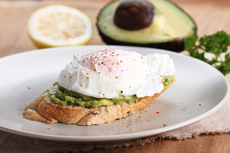 Breakfast, poached eggs with avocado salad on toastの写真素材