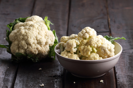 fresh cut cauliflower for cooking in a bowl on rustic wooden backgroundの写真素材
