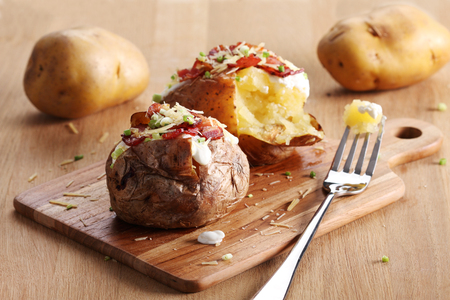 hot baked potatoes topped with bacon, cheese and soured creamの写真素材