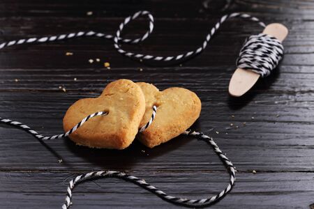 Heart shaped sugar cookies tied with rope on black wooden background