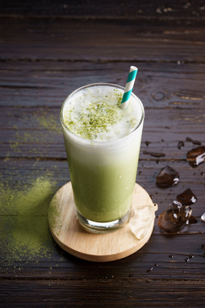 glass of iced green tea latte on wooden backgroundの写真素材