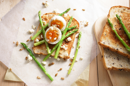 steamed asparagus, soft boiled egg and crumbled feta cheese on toast breadの写真素材