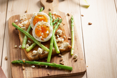 steamed asparagus, soft boiled egg and crumbled feta cheese on toast breadの写真素材
