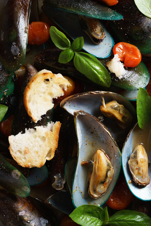 baked mussels with tomato and fresh sweet basil in baking trayの写真素材
