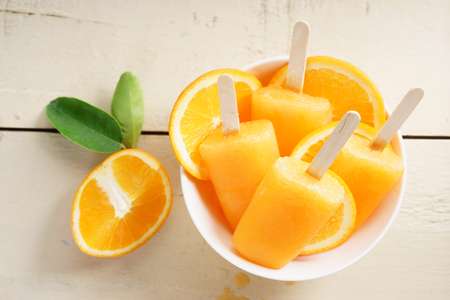 orange ice pops fresh summer fruit sweet dessert in a yellow polka dot cupの写真素材