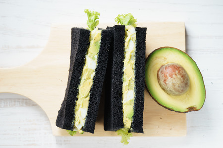 Sandwich of black charcoal bread with egg and avocado for healthy breakfast