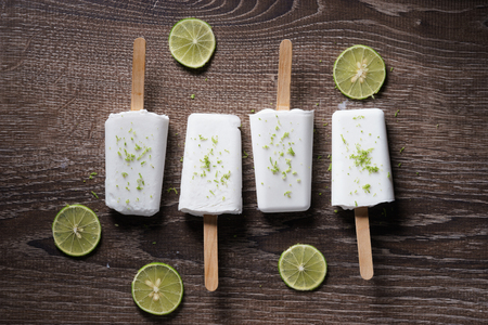 coconut ice pops ,coconut ice cream bars, with fresh green lime zest on wooden backgroundの写真素材