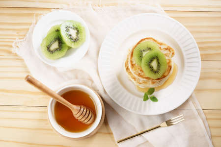 pile of pancakes with honey syrup and fresh kiwi slicedの写真素材