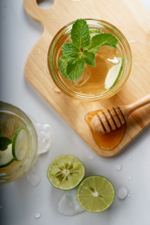 lime and honey iced drinks with cucumber sliced on white marble tableの写真素材