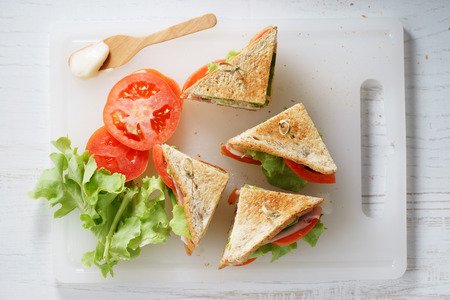 Sandwich of whole wheat bread with ham, cheese and fresh tomato, triangle cut, top viewの写真素材