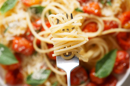 spaghetti with roasted cherry tomato and fresh basil in a white plateの写真素材