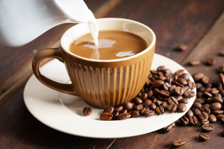 cup of hot coffee with milk on wooden table with coffee beansの写真素材
