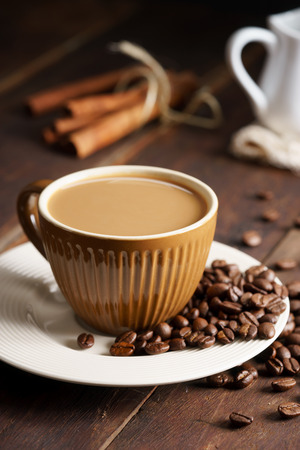 cup of hot coffee with milk on wooden table with coffee beansの写真素材