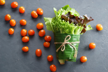 fresh vegetables in banana leaf wrap. green mix salad on dark backgroundの写真素材
