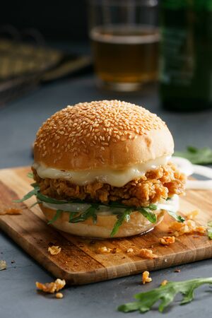 Tasty fired chicken with arugula and mayonnaise sauce served on wooden boardの写真素材