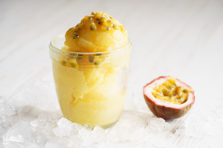refreshing pineapple and passionfruit sorbet with ice on white wooden backgroundの写真素材