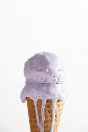 melting purple color ice cream on waffle coneの写真素材