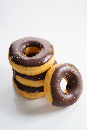 stack of donuts with chocolate glaze and rainbow sugar sprinklesの写真素材