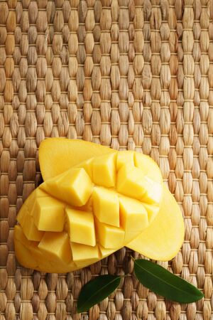 mango, summer fruit. fresh cube sliced on wickerwork backgroundの写真素材
