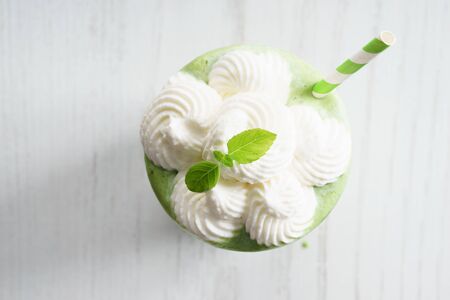 green smoothie glass top with whip cream on white wooden backgroundの写真素材