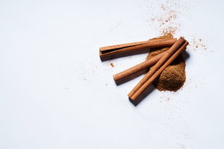 cinnamon sticks and ground cinnamon on white background. top view.