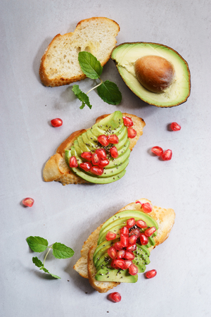 Avocado sandwich on sliced  bread toast made with fresh sliced avocados and pomegranate seeds.の写真素材