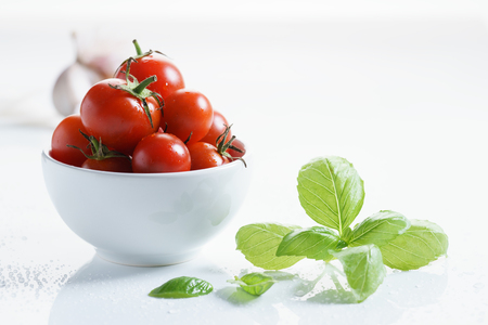 ripe tomatoes with fresh sweet basil, on a white background.の写真素材