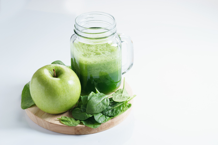 healthy green drink with fresh spinach and green apple on white backgroundの写真素材
