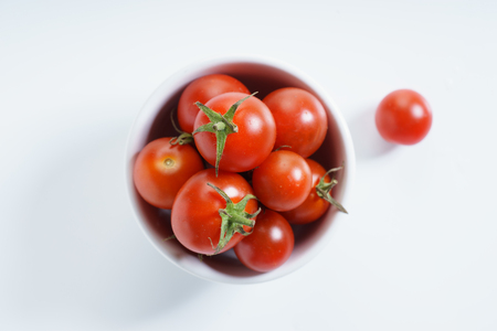ripe tomatoes in a bowl, top view, on a white background.の写真素材