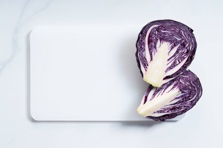 red cabbage sliced in half with white cutting boardの写真素材