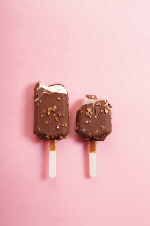 chocolate ice cream lolly with almond flakes on pink backgroundの写真素材