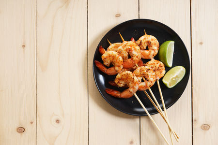 Grilled shrimps on skewer with lime slices and saladの写真素材