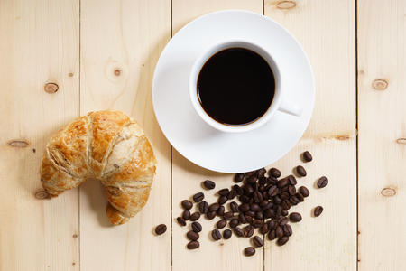 Cup of coffee and croissant on wooden table, breakfast conceptの写真素材