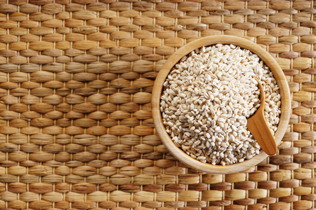 Barley grains in wooden bowl on wooden backgroundの写真素材