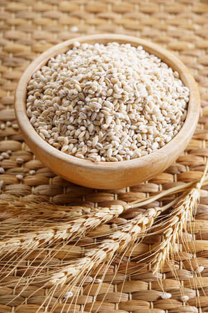 Barley grains in wooden bowl on wooden backgroundの写真素材