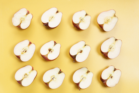 sliced red apples in a row on yellow backgroundの写真素材